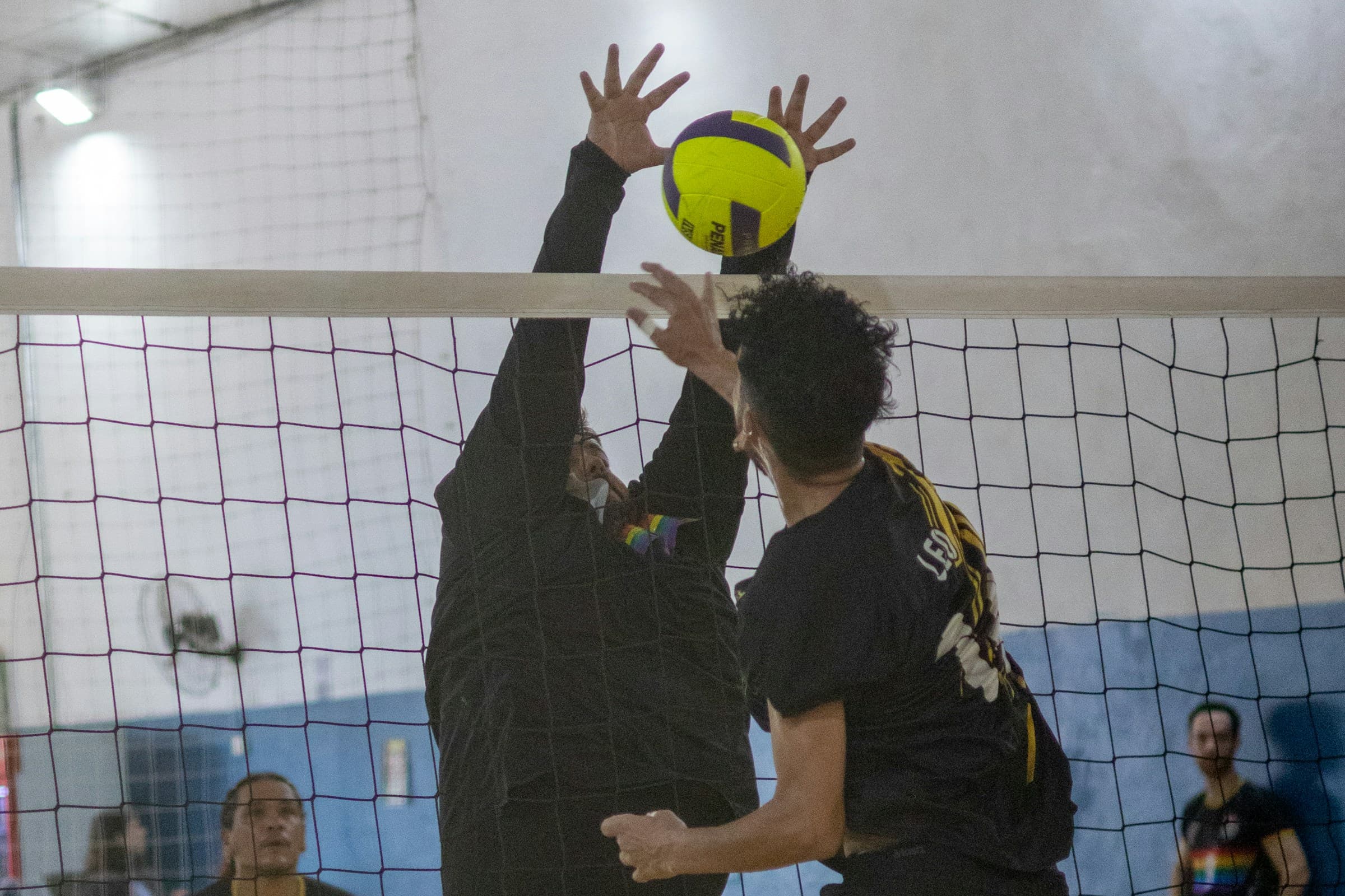Indoor volleyball players competing together at the net